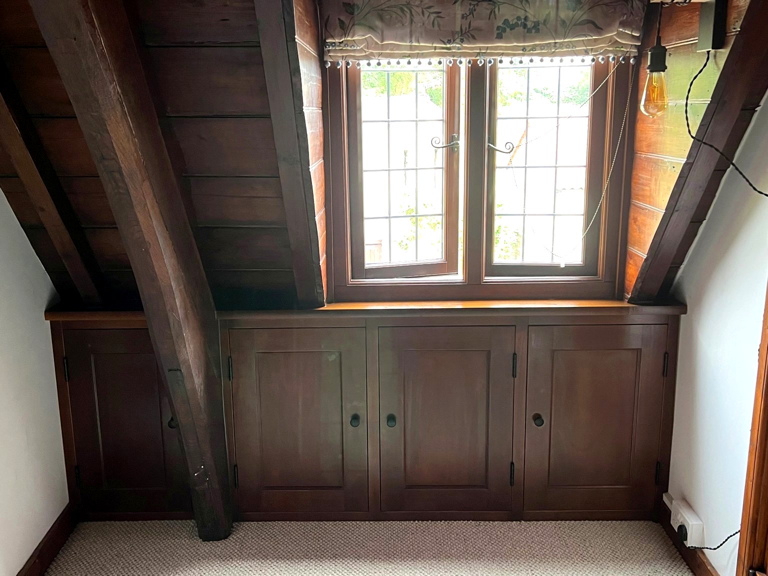 Under‑eaves storage cabinets in dark wood, handcrafted in Wellingborough