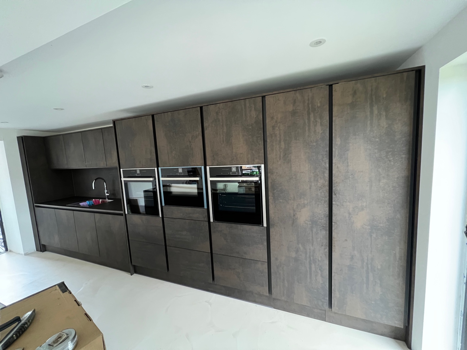 Modern floor‑to‑ceiling cabinet wall with integrated ovens
