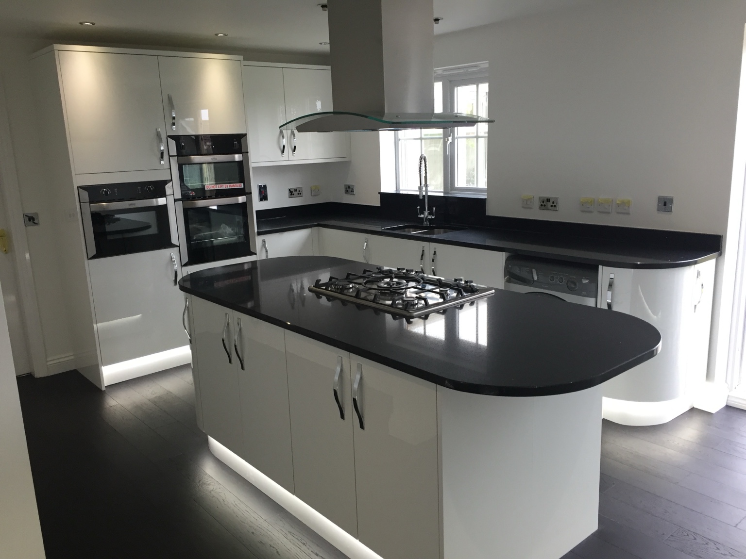 Modern white kitchen with black countertops and built‑in appliances